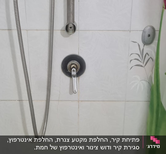 ברז מקלחת עם צינור מתכת על קיר אריחים